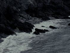 the water is choppy and foamy next to some rocks