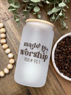 a coffee mug next to a bowl of beans and some leaves on a wooden table