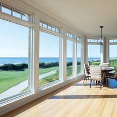 a large open living room with lots of windows overlooking the ocean and golf course in the distance