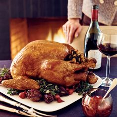 a large turkey sitting on top of a white plate next to a glass of wine