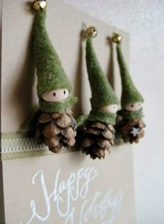 three little gnomes with pine cones on their heads are hanging from a wall ornament