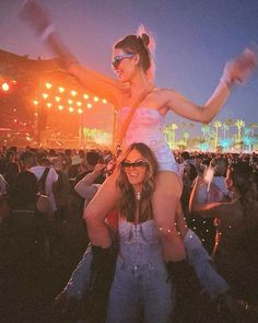 two women in front of an audience at a music festival with their arms around each other