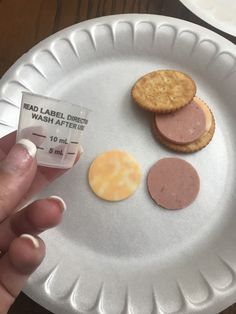 a hand holding a plastic plate with three different types of cookies on it and a label that says dead label direct wash after