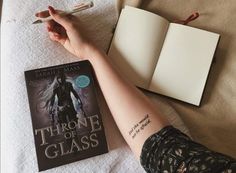 a person's arm resting on a bed next to a book and an open notebook