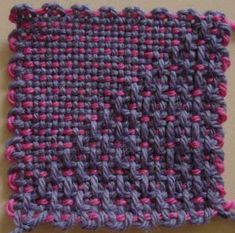 a close up of a knitted piece of cloth with pink and gray squares on it