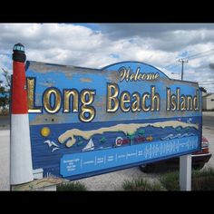 the sign for long beach island is painted blue and white with an orange light house on top