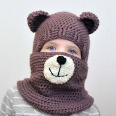 a young boy wearing a knitted bear hat and neckwarf for cold weather