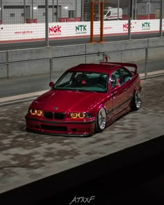 a red car parked in front of a fence