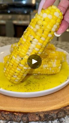 a person is dipping corn on the cob with mustard