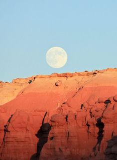 the moon is setting over some red rocks