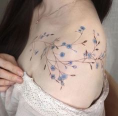 a woman's chest with blue flowers on it and the top part of her breast