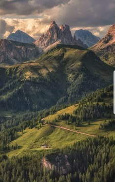 the mountains are covered in green grass and trees, with a road winding through them