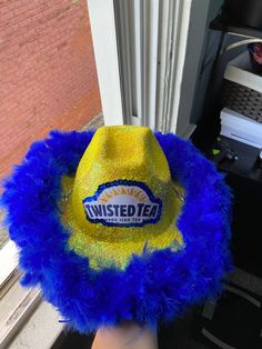 a yellow and blue hat with the words twisted tea on it sitting in front of a window