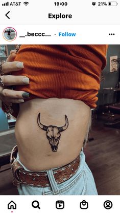 a woman's stomach with a bull skull tattoo on her lower back and side