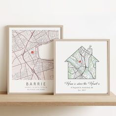 two framed maps sit on a shelf next to each other, one with a house and the other with a map