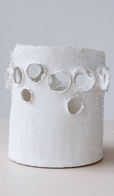 a white vase with holes in it on a table