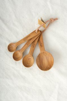 five wooden spoons with writing on them are lined up against a white cloth background