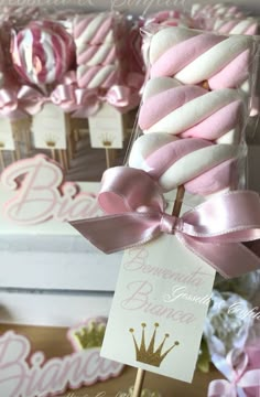 pink and white baby shower favors in a box with ribbon on top, sitting next to other sweets