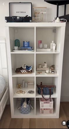 a white book shelf filled with shoes and bags