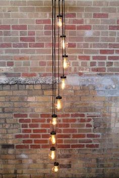 a light fixture hanging from the ceiling in front of a brick wall with lights on it