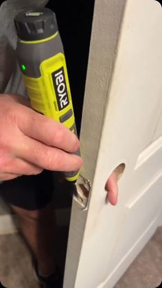 a person opening a door with a screwdriver in their hand and a bottle of glue on the door handle