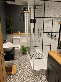 a bathroom with black and white tile flooring, a toilet, shower stall and sink