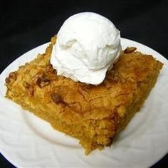 a piece of pie on a white plate with whipped cream on top, sitting on a black surface