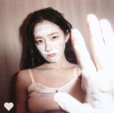 a woman holding up her hand with white paint on it's face and hands