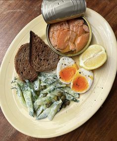 a white plate topped with eggs, bread and asparagus on top of a wooden table