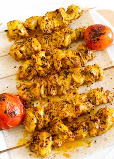 chicken skewers with tomatoes and spices on a white plate, ready to be eaten