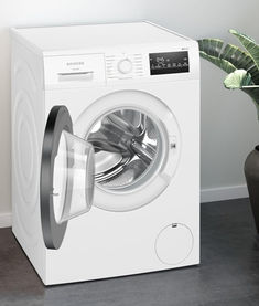 a white washing machine sitting next to a plant