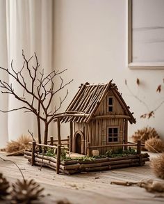 a small wooden house sitting on top of a table next to a tree with no leaves