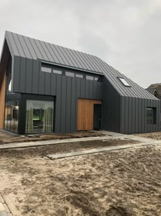 a house that has been built in the middle of dirt and sand, with two large windows