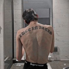 a man with tattoos on his back standing in front of a bathroom mirror