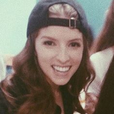 a young woman is smiling and wearing a hat