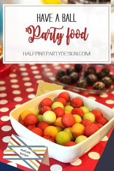 a bowl full of fruit sitting on top of a table with a sign that says have a ball party food