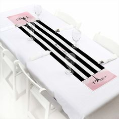 the table is set with black and white striped placemats, wine glasses, and napkins