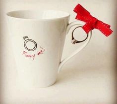 a white coffee cup with a red bow on the handle and some words written in spanish