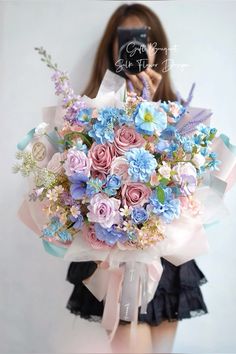 a woman holding a bouquet of flowers in front of her face while taking a selfie