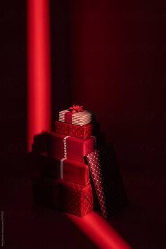 a stack of wrapped presents sitting on top of each other in front of a red light