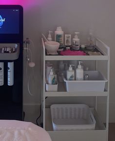 a shelf with bottles, soaps and lotions on it next to a bed