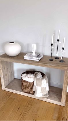 a wooden shelf with candles and a basket on it