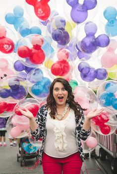 a woman standing in front of mickey mouse balloons