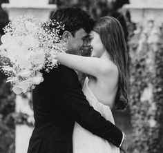 a man and woman embracing each other while holding flowers