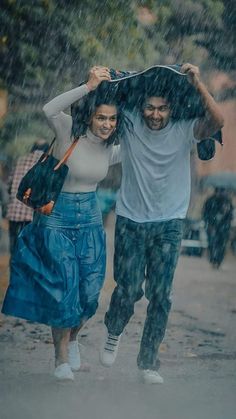 two people walking in the rain with an umbrella over their heads and one person carrying something on his shoulders