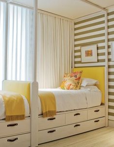 a bedroom with yellow and white striped walls, drawers and a bed in the middle