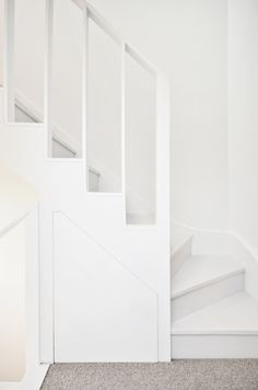 there is a white stair case next to the wall and carpeted floor in this room