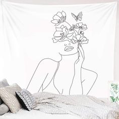 a white wall hanging over a bed with a drawing of a woman and flowers on it