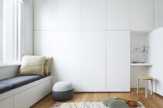 a white room with a bench, window and rug on the wooden floor next to it