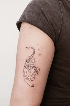 a woman with a tiger tattoo on her left arm and the other arm behind her